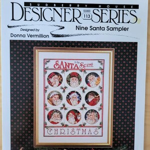 May include: A "Sudberry House Designer Series" pattern for a "Nine Santa Sampler" cross-stitch project. The design features nine Santa Claus portraits in circular frames, with the words "Santa Spirit" and "Christmas".