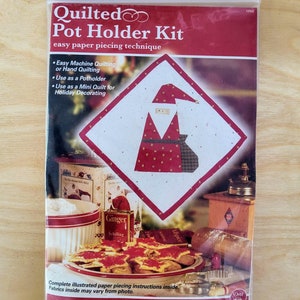 May include: A quilted pot holder kit featuring a Santa Claus design. The kit includes easy paper piecing instructions and is perfect for holiday decorating.