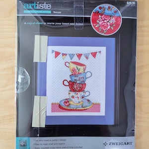 May include: A counted cross-stitch pattern featuring a stack of teacups with a floral design. The pattern is titled "Teacups" and is part of the "artiste" counted cross-stitch collection. The finished size is 11 inches by 14 inches.