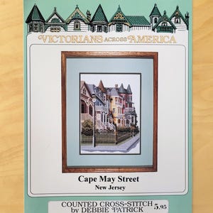 May include: A white ceramic mug with a black handle and the text "But First, Coffee" in a bold, black font. The mug is set against a blurred background, suggesting a cozy setting.