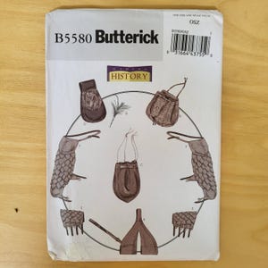 May include: A Butterick B5580 sewing pattern envelope featuring illustrations of various historical accessories including pouches, bags, and gauntlets. The white paper envelope displays the Making History logo, a barcode, and the text B5580 Butterick.