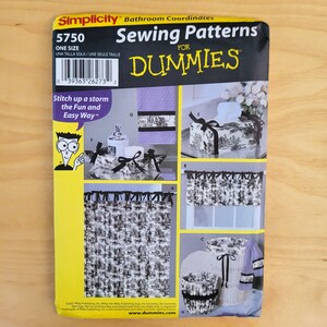 May include: A Simplicity sewing pattern for bathroom coordinates, featuring a black and white toile design. The pattern includes instructions for a shower curtain, window valance, tissue box cover, and other accessories. The cover reads "Sewing Patterns for Dummies."
