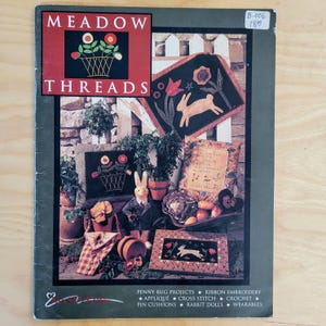 May include: A magazine cover for Meadow Threads featuring a variety of needlework projects, including a bunny rabbit, a floral design, and a cross stitch pattern. The cover also includes the text "Penny Rug Projects, Ribbon Embroidery, Applique, Cross Stitch, Crochet, Pin Cushions, Rabbit Dolls, Wearables".