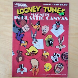 May include: A red leaflet featuring Looney Tunes magnets in plastic canvas. The cover displays various cartoon characters, including Bugs Bunny, Daffy Duck, and Sylvester. The leaflet includes the text "Looney Tunes Magnets in Plastic Canvas" and the price.