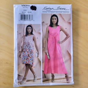 May include: A sewing pattern package featuring two dress designs. The package is white with the text "V9314" and "Kathryn Brenne" printed on it. One dress is floral, and the other is a solid pink color.