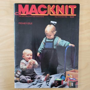 May include: The cover of "MacKnit," The Machine Knitters Magazine, features two babies in knitted outfits. The magazine's title is in red, with the issue's season and year, Fall/Winter 1985, displayed in the upper right corner.