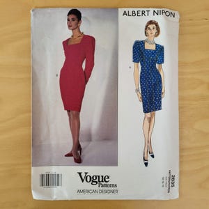 May include: Vogue Patterns sewing pattern featuring two dress designs by Albert Nipon. One dress is a long-sleeved, red sheath dress. The other is a blue dress with white polka dots and short sleeves. The pattern is for sizes 14-16-18.