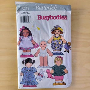 May include: A vintage sewing pattern for making dolls. The pattern is for Busybodies by Butterick and is number 3221. The pattern includes instructions for making five dolls, including a doll with a blue dress, a doll with a pink dress, a doll with a yellow dress, a doll with a white dress, and a doll with a blue and white dress.
