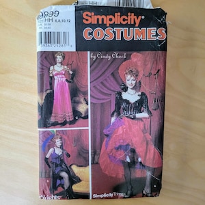 May include: A Simplicity Costumes pattern envelope featuring three costume designs. The envelope has a black and red color scheme with the text "Simplicity Costumes" and "by Cindy Chock". The designs include a pink gown, a black and purple outfit, and a red and black dress.