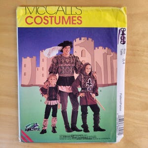 May include: A vintage McCall's Costumes pattern envelope featuring illustrations of medieval costumes. The cover displays three figures in detailed outfits, including a knight and a nobleman, set against a castle backdrop. The pattern size is 3,4.