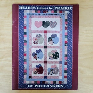 May include: A book titled "Hearts from the Prairie" with a subtitle "A Book for Applique and Cross Stitch" by Piecemakers. The cover features a quilt design with a patchwork of hearts and dolls.