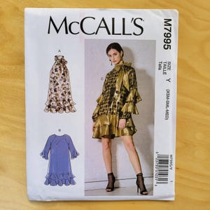 May include: McCall's sewing pattern M7995. The pattern features illustrations of three different dress designs. The cover shows a model wearing a gold metallic dress. The pattern size is Y (XSM-SML-MED).
