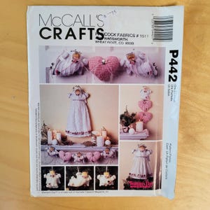 May include: McCall's Crafts pattern P442 featuring various handmade angel and heart ornaments. The cover displays multiple images of the finished crafts, including angels and heart-shaped decorations. The text "Woman's Day" is visible.
