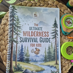 May include: A spiral-bound book titled "The Ultimate Wilderness Survival Guide for Kids" with a forest scene illustration. A green and wooden compass and a green toy are visible. The book is designed for children aged 5-12 years.