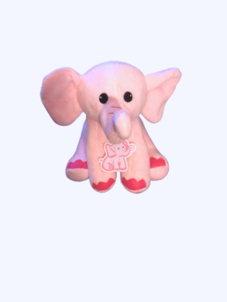 May include: A pink plush elephant toy with a small pink elephant design on its chest. The elephant has large ears and a long trunk.