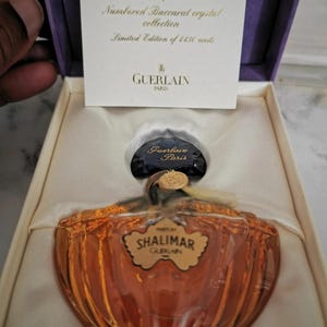 Può includere: Un flacone da 30 ml di profumo Shalimar in un flacone di cristallo Baccarat. Il flacone è in una scatola viola con un'etichetta dorata che recita "Shalimar 30 ml Parfum bottle Numbered Baccarat crystal collection Limited Edition of 4450 units Guerlain Paris".