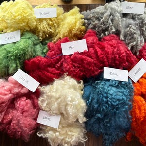 Puede incluir: Una colección de fibras rizadas de colores, etiquetadas con sus colores: amarillo, verde, rojo, rosa, blanco, azul, naranja y plateado.