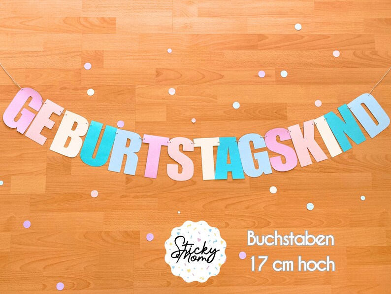 May include: A pastel coloured banner with the German words "Geburtstagskind" which translates to "Birthday Child". The banner is made of paper and is strung together with white string. The letters are 17 cm high.