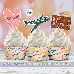 Op de afbeelding: Printbare cupcake-toppers en -verpakkingen met een reisthema. De toppers bevatten een hart met de tekst "Bon Voyage", een groen vliegtuig met de tekst "On My Way" en een bruine koffer met reisstickers. De verpakkingen hebben een patroon van kleurrijke vliegtuigen en harten.