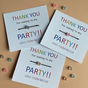May include: Three white thank you cards with black string and colorful beads that spell out "PARTY!" Each card says "Thank you for coming to my party! Love from Molly."