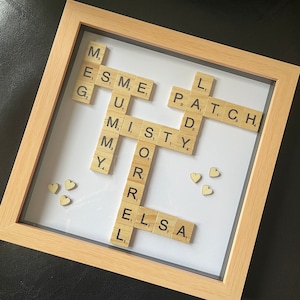 May include: A framed Scrabble tile artwork with the words "L PATCH", "DADDY", "MISTY", "MY", "OR", "RE", "ELSA" and "ME" spelled out. The artwork is decorated with small wooden hearts.