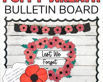 May include: A bulletin board decorated with a poppy wreath and the words "Lest We Forget". The wreath is made of red paper poppies and green leaves. There are also smaller paper poppies hanging from a string across the top of the board.
