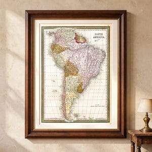 Puede incluir: Un mapa enmarcado de estilo antiguo de América del Sur con regiones codificadas en colores pastel apagados, etiquetas de texto en negro y una cuadrícula de líneas de latitud y longitud. El mapa tiene un marco de madera marrón oscuro con un paspartú crema.