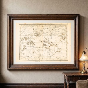 May include: A framed vintage celestial map featuring the constellations Andromede, Persee, and Le Triangle. The print displays intricate black line drawings of stars and mythological figures on a cream background, enclosed in a dark wood frame.