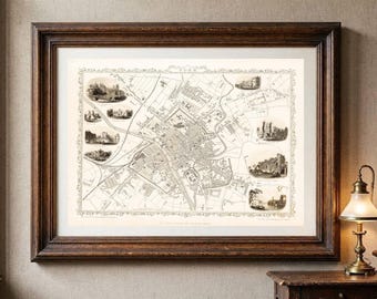 Peut inclure: Une carte ancienne encadrée de York, en Angleterre, présentée dans un cadre en bois brun foncé avec un passe-partout blanc. La carte en noir et blanc présente des tracés de rues détaillés et plusieurs petites vignettes illustrées.