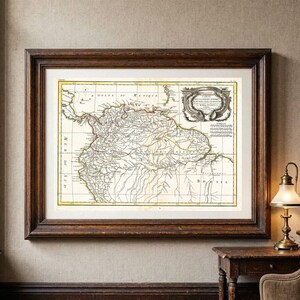 Peut inclure: Une carte ancienne de l'Amérique du Sud encadrée dans un cadre en bois brun foncé. La carte présente des lignes à l'encre noire sur un fond crème avec des reflets jaunes le long des côtes et un cartouche décoratif dans le coin supérieur droit.
