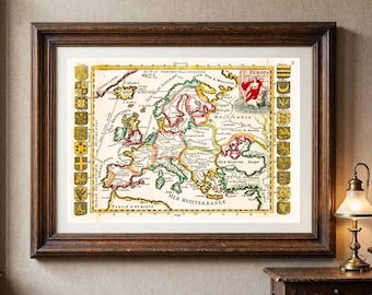 Op de afbeelding: Een ingelijste antieke kaart van Europa met handgekleurde grenzen en regio's. De kaart bevat decoratieve heraldische wapens langs de linker- en rechterkant, met de tekst EVROPA duidelijk zichtbaar in de rechterbovenhoek van de kaart.