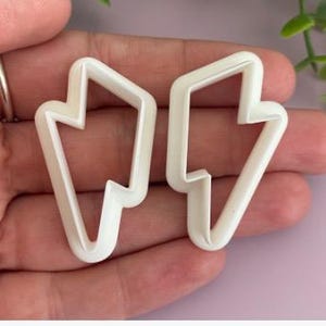 May include: A white ceramic mug with a black handle and the text "But First, Coffee" in a black, handwritten-style font. The mug is on a white surface.