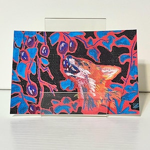 May include: A rectangular art print featuring a stylized fox with orange and white fur reaching up toward dark purple berries on a branch. The background is black with vibrant blue and red foliage patterns surrounding the fox and fruit.