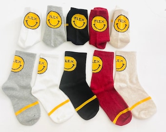 May include: Ten pairs of socks with a yellow smiley face and the word "FLEX" in black lettering. The socks are in various colors including gray, white, black, red, and beige.