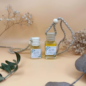 Peut inclure: Deux petits flacons en verre remplis d'un liquide jaune, surmontés d'un bouchon en bois clair et d'un cordon tressé. Les étiquettes portent le texte ACCORD PRECIEUX Diffuseur voiture et une petite icône de drapeau français.