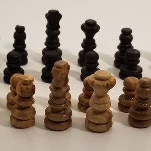 May include: A set of wooden chess pieces, with black and natural wood colors. The pieces are arranged in two rows, with the black pieces on the top row and the natural wood pieces on the bottom row.