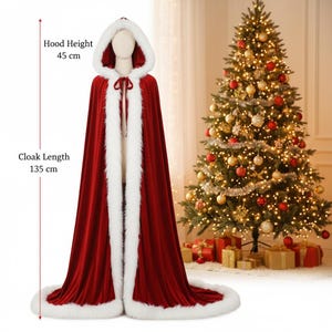 May include: A red velvet cloak with a white faux fur trim and hood. The cloak is 53 inches long and the hood is 18 inches high. The cloak is tied at the neck with a red ribbon. A Christmas tree is in the background.