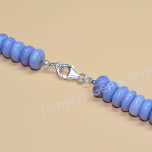 May include: A close-up of a light blue gemstone necklace with a silver clasp. The necklace is made of round beads and has a simple design.