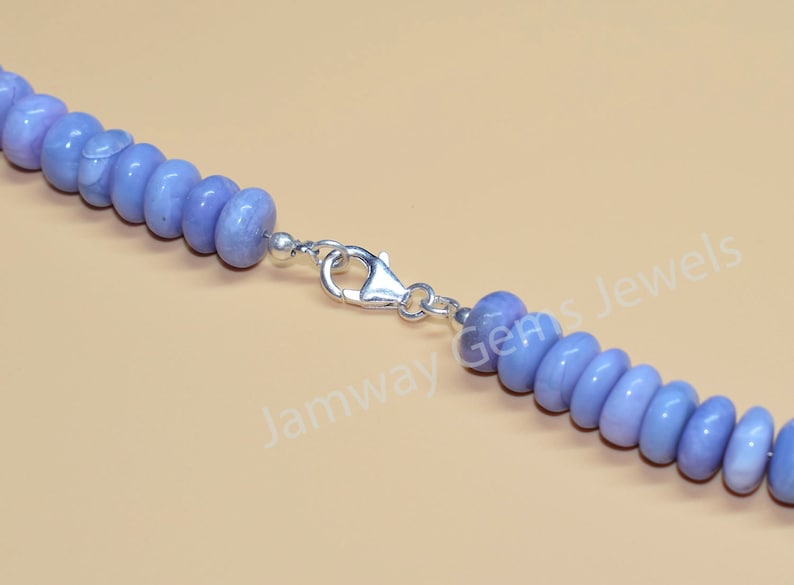 May include: A close-up of a light blue gemstone necklace with a silver clasp. The necklace is made of round beads and has a simple design.