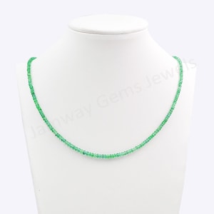 Pode incluir: Um colar delicado composto por pequenas contas redondas de um verde vibrante. O colar é exibido em um manequim branco, mostrando seu design elegante. As contas parecem ser de tamanho uniforme e enfiadas, criando uma peça de joalheria refinada.