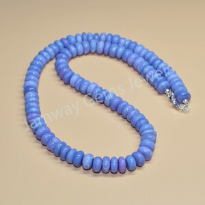 May include: A light blue gemstone bead necklace with a silver clasp. The beads are round and have a smooth, polished finish.