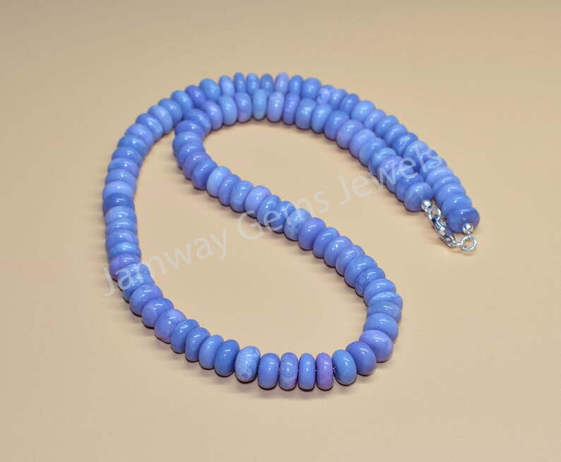 May include: A light blue gemstone bead necklace with a silver clasp. The beads are round and have a smooth, polished finish.