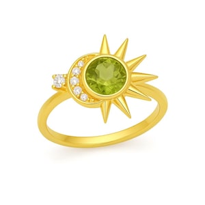 Peut inclure: Une bague en or avec un motif soleil et lune. Le soleil a des rayons pointus autour d'une grosse pierre verte claire ronde. Un croissant de lune est orné de petits diamants transparents. L'anneau est en or poli simple.