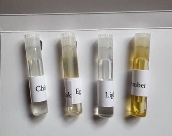 May include: Four small glass vials with clear and amber liquids. Each vial has a white label with black text: "Chi", "Eg", "Lig", and "Amber". The vials have clear plastic caps and are arranged against a white background.