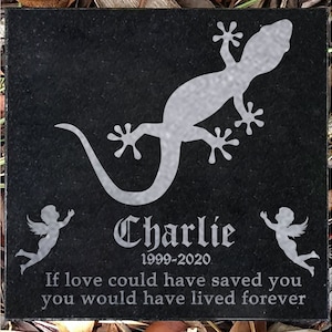 Op de afbeelding: Zwarte granieten gedenksteen met een wit gekko-silhouet, twee witte engel-silhouetten en de tekst "Charlie 1999-2020 Als liefde je had kunnen redden, zou je voor altijd hebben geleefd".