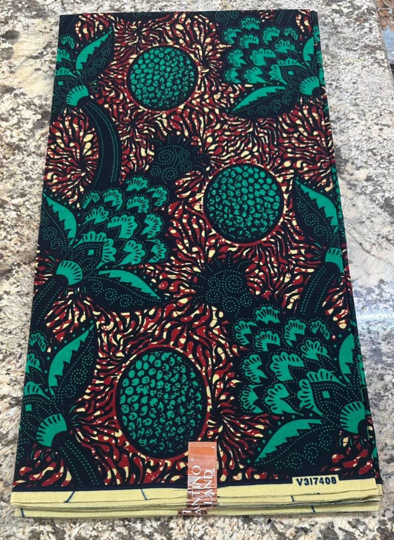 May include: A folded piece of fabric featuring a repeating pattern of large green circular shapes with textured black dots, surrounded by stylized green leaves and intricate red and yellow radiating lines on a deep black background.