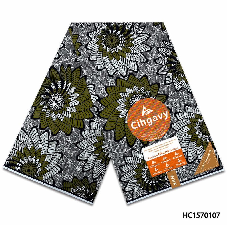 May include: A folded piece of fabric featuring a repeating pattern of large, stylized olive green and white spiral flowers on a dark gray background with a fine white geometric web design. An orange circular label reads Cihgavy and Cottonhaus.