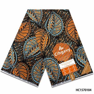 May include: A piece of fabric featuring a repeating pattern of large orange and light blue leaves on a dark brown background. The textile includes a circular logo with the text Cihgavy and a rectangular label with the text Cottonhaus wax.