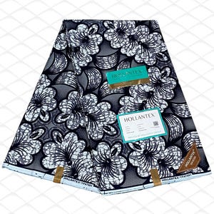 May include: A folded piece of fabric featuring a black and white floral pattern with intricate line work. The textile includes a teal rectangular label with the text HOLLANTEX and a brown triangular tag with the text HOLLANTEX 16436566.