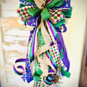 Peut inclure: Un grand nœud festif réalisé avec un ruban vert, violet et or. Le nœud est noué avec un ruban à carreaux et un ruban en maille dorée est tissé dans toute sa longueur.